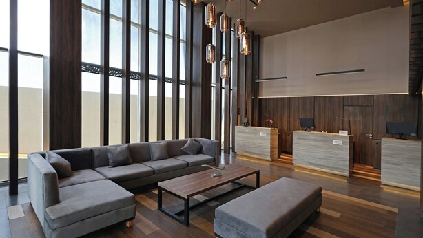 A modern lobby with a sectional sofa, a small table, and a reception desk.