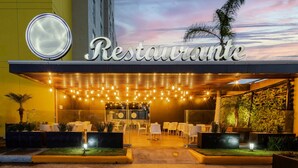 A restaurant with a sign reading "Restaurante" and outdoor seating with string lights.