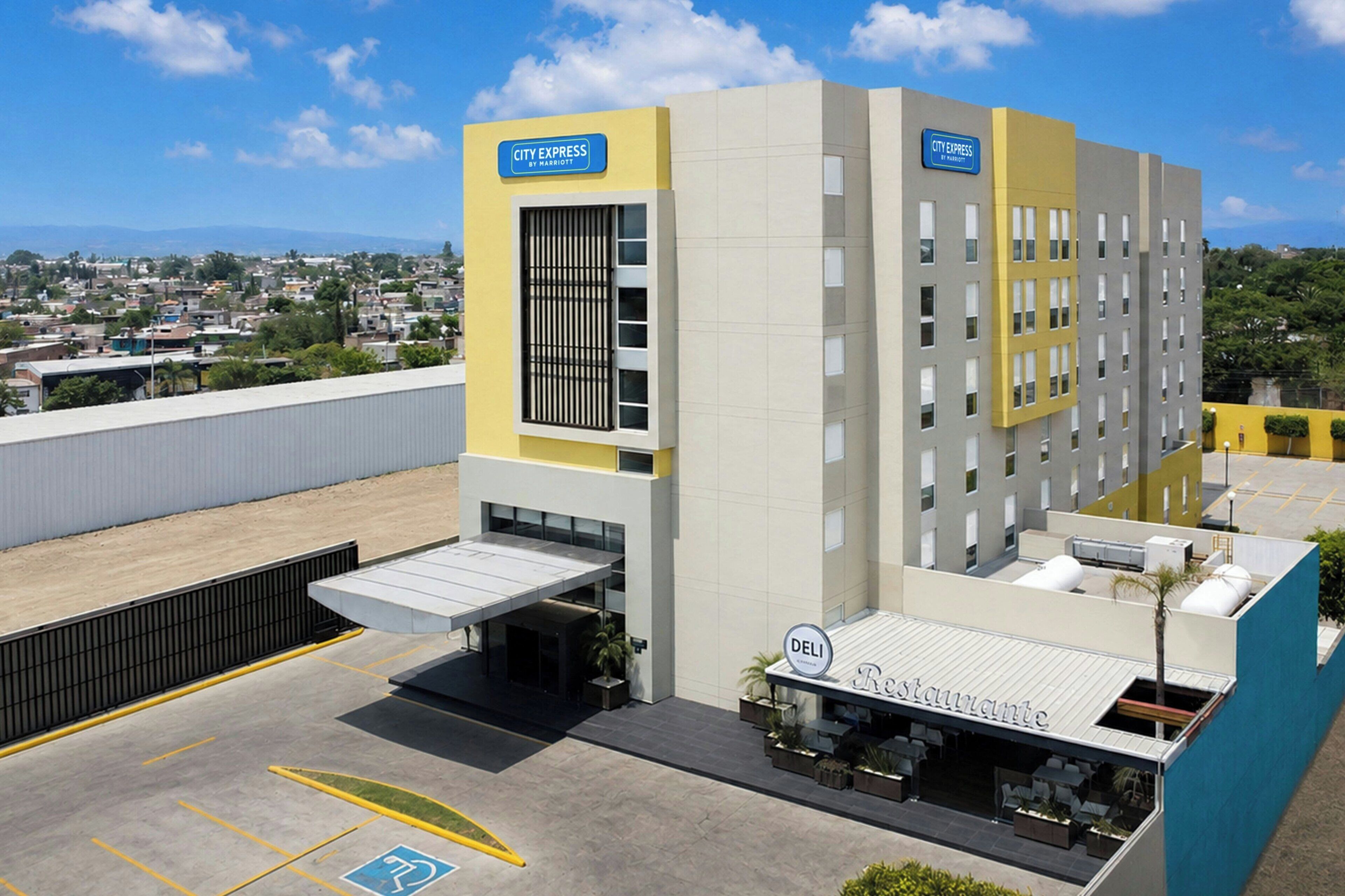 A hotel with a City Express sign, a Deli Restaurante, and a parking lot with handicapped accessibility.