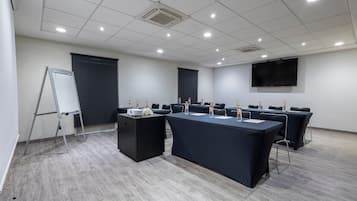 Un salón de conferencias con una gran mesa, sillas, un proyector y una pantalla.