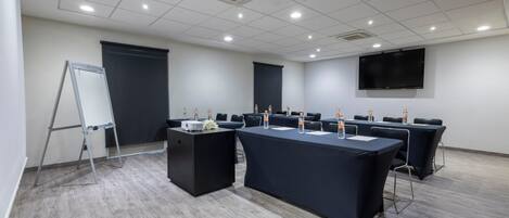 A conference room with a large table, chairs, a projector, and a screen.
