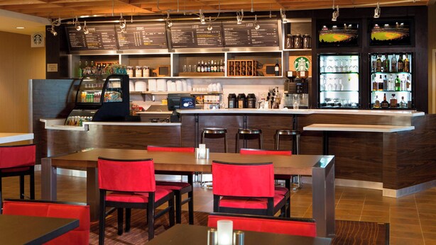 Een restaurant met een bar, een houten plafond en rode stoelen.