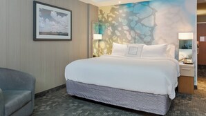 Een hotelkamer met een groot bed, een stoel, een aan de muur hangend schilderij en een decoratief muurschildering.