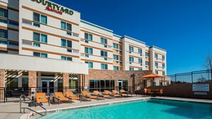 Een Courtyard Marriott hotel met een zwembad, terras en een gevel van natuursteen.