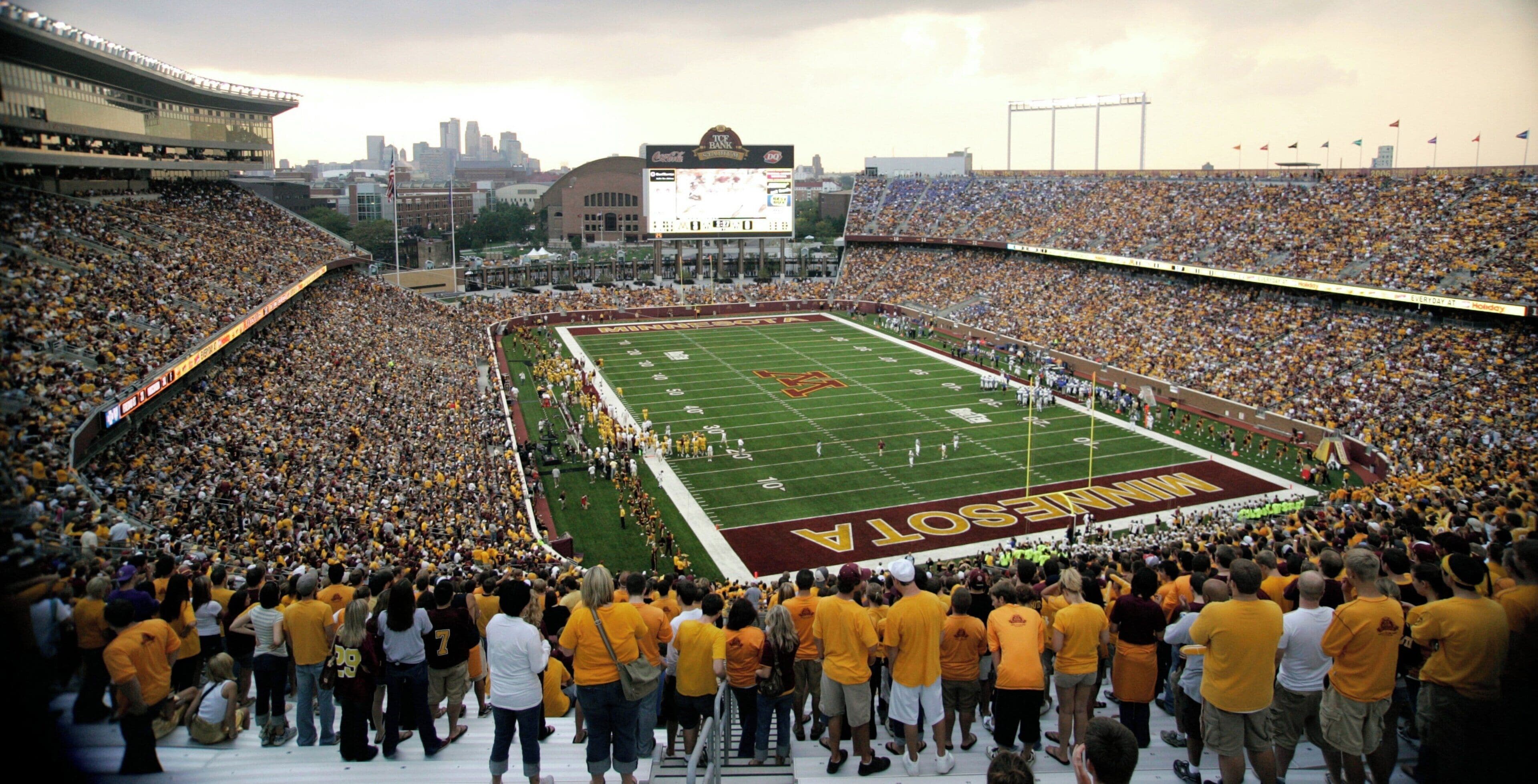 A large stadium filled with spectators, with a football field in the center.