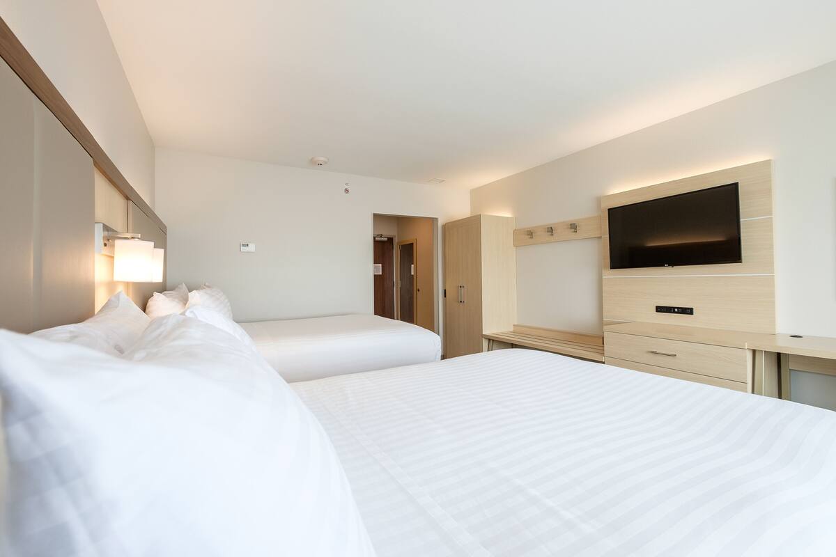 A hotel room with two beds, a TV, a desk, and a wardrobe.