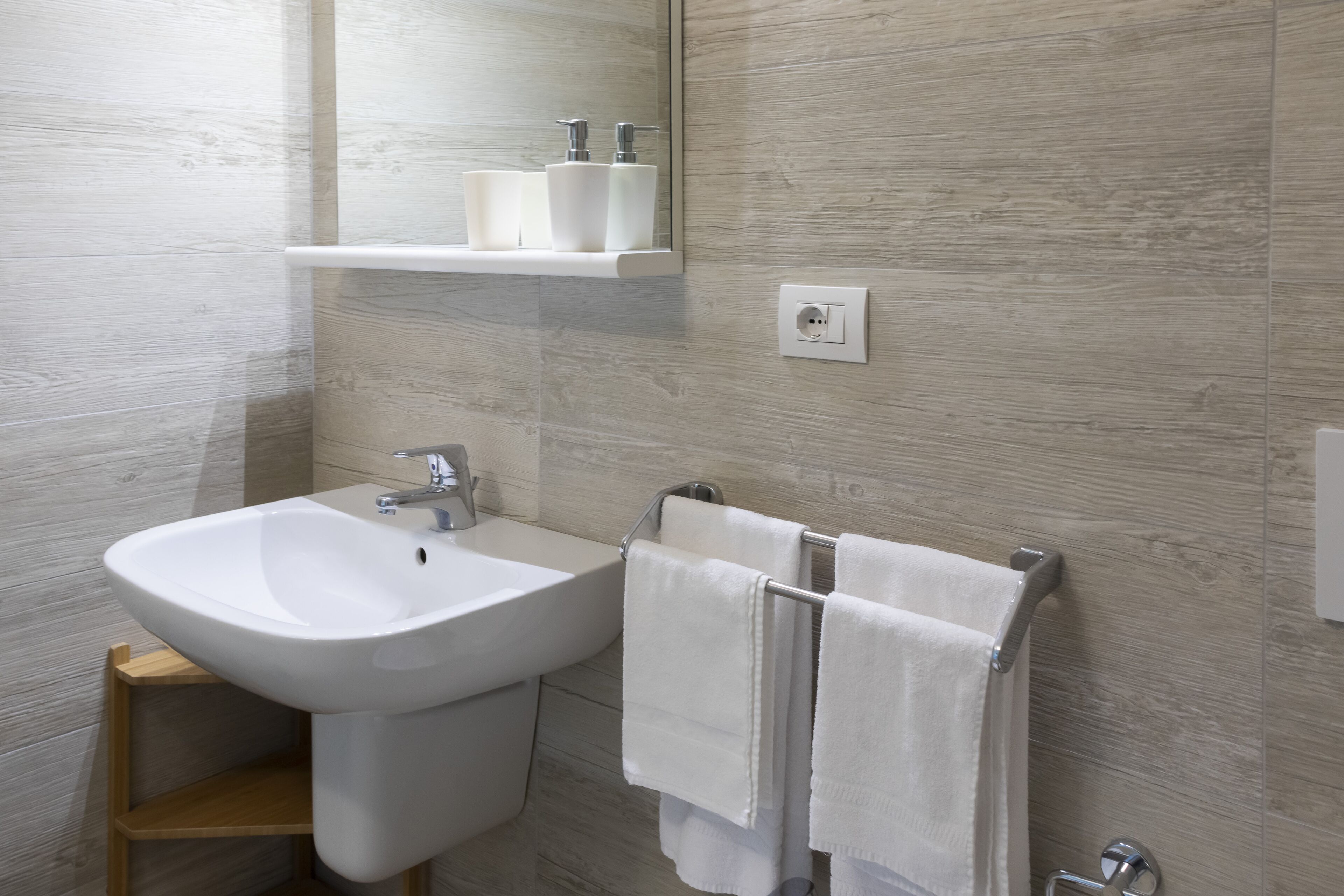 Une salle de bain avec un lavabo blanc, un miroir et un porte-serviettes.