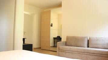 Ein modernes Hotelzimmer mit einem Bett, einer Couch, einem Schreibtisch und einem Kleiderschrank.