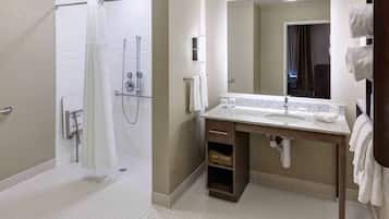 Un baño moderno con ducha, lavamanos con espejo y un perchero para toallas.