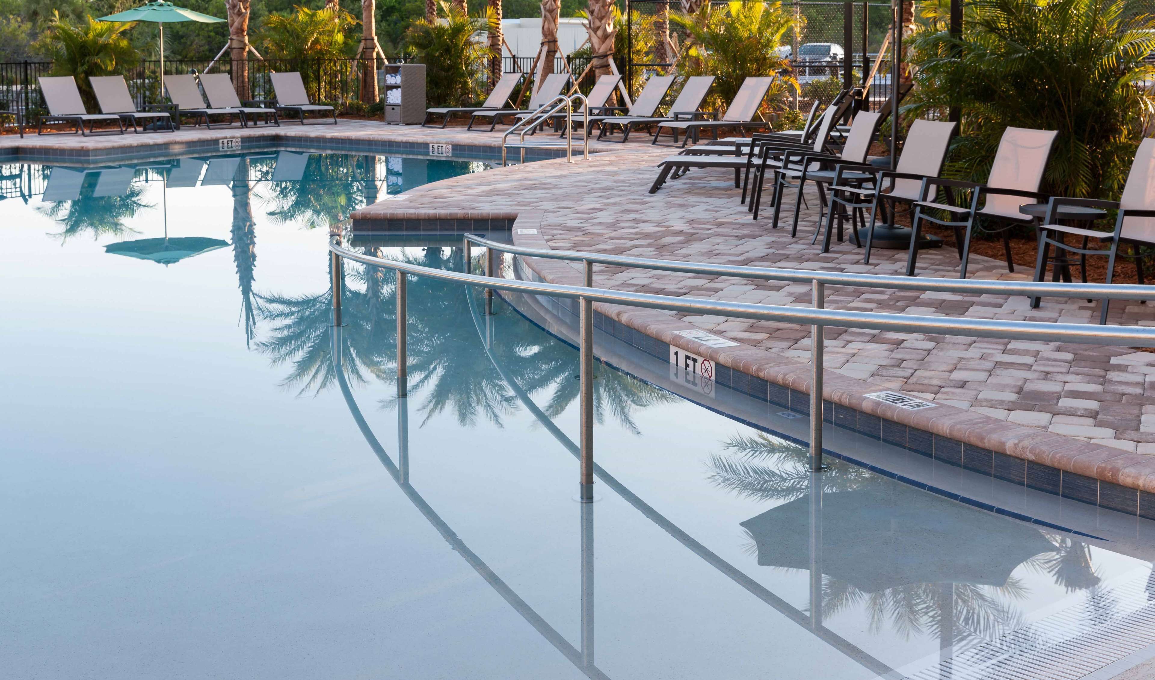 A swimming pool with lounge chairs and a tiled deck.