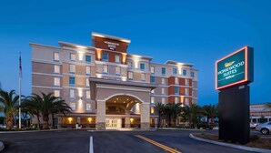 A multi-story hotel with a prominent entrance, a signboard, and a parking area. - Homewood Suites by Hilton Cape Canaveral-Cocoa Beach (Cape Canaveral)