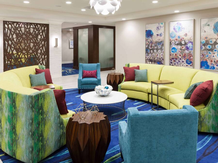 A modern lounge area with a yellow sofa, blue armchairs, and a round coffee table.