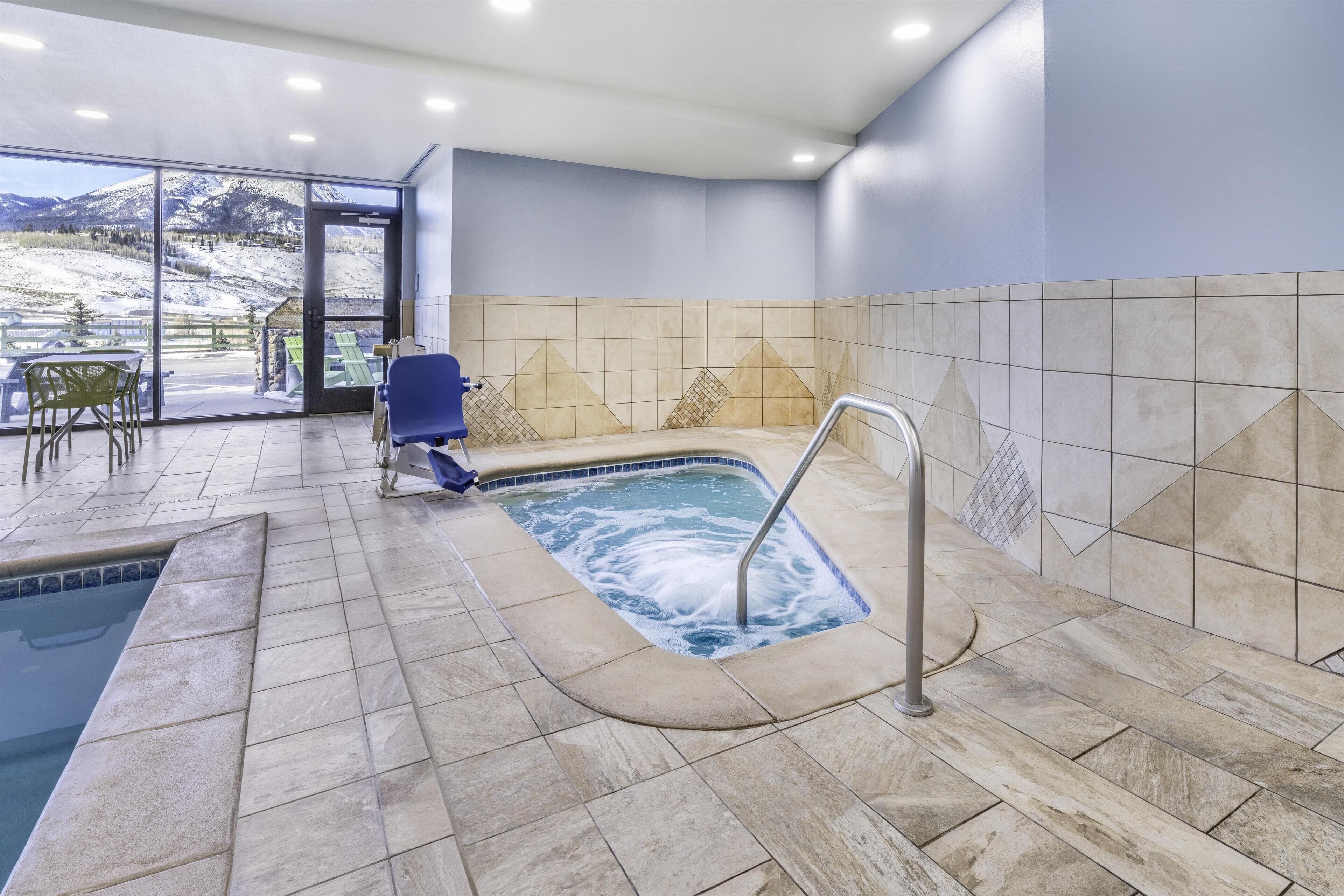 A spa area with a hot tub, seating, and a view of a snowy mountain.