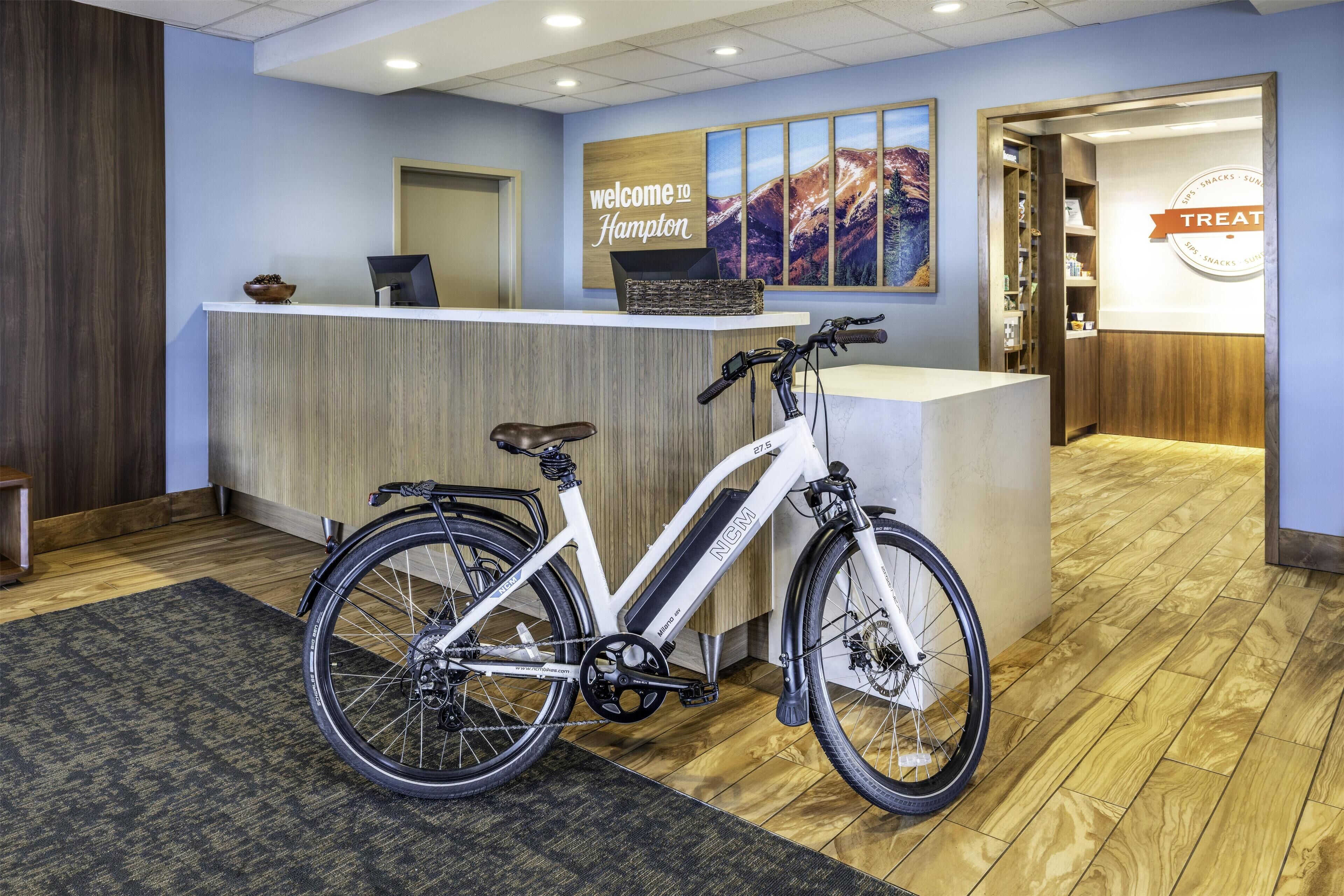 Un espace d’accueil comprenant un comptoir de réception, un vélo et une enseigne murale sur laquelle on peut lire : « Bienvenue à Hampton ».