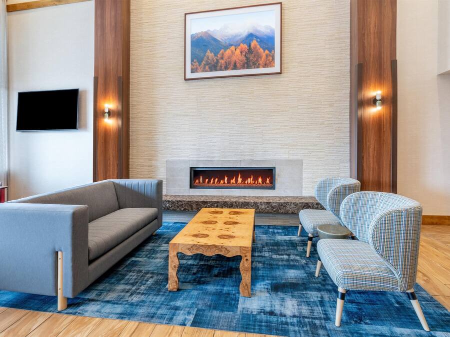 Un moderno salón con chimenea, un televisor de pantalla plana y un cuadro grande de un paisaje montañoso.