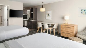 A hotel room with two beds, a dining table with chairs, a kitchenette, a TV, and a lamp. - TownePlace Suites by Marriott Waco South (Waco)