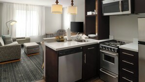 A modern kitchen with a dishwasher, stove, microwave, and a dining area with a sofa and a lamp. - TownePlace Suites by Marriott Waco South (Waco)