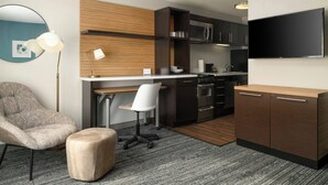 A modern kitchen with dark cabinetry, a built-in oven, and a flat-screen TV mounted above the counter. - TownePlace Suites by Marriott Waco South (Waco)