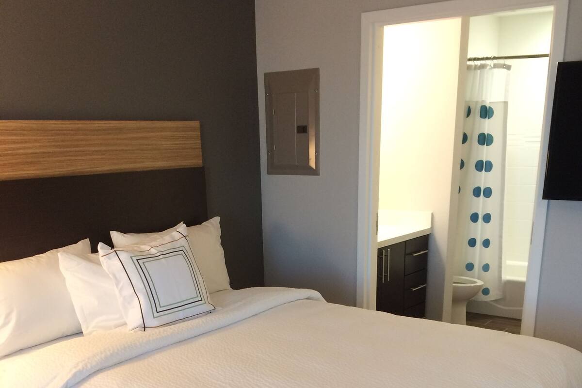 Una cama bien hecha con sábanas blancas y cabecera de madera.