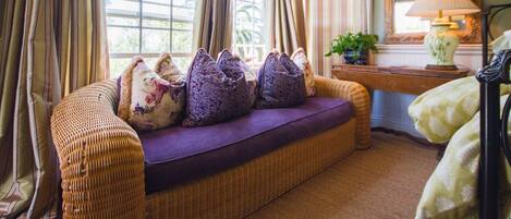 A cozy room with a wicker sofa, a wooden desk, and a large mirror.