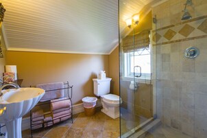 Un baño con ducha de vidrio, lavamanos, inodoro y ventana.