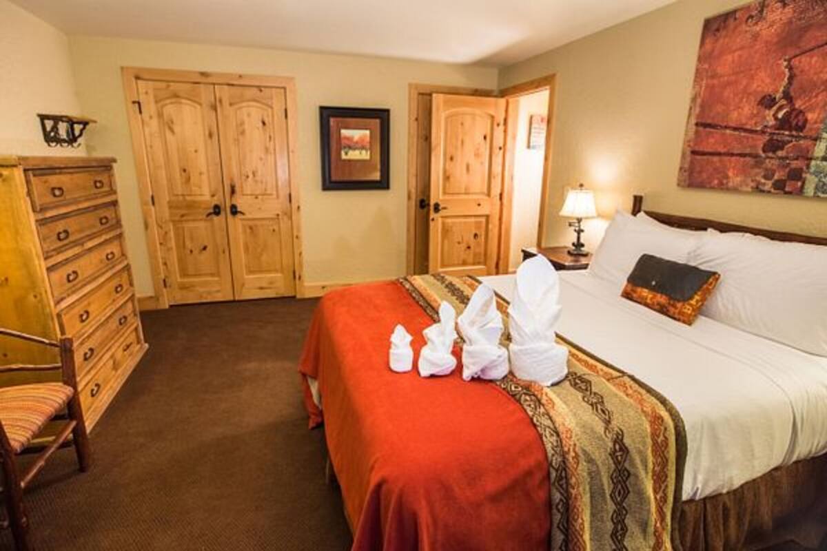 Una habitación de hotel con cama, cómoda, silla y puerta.