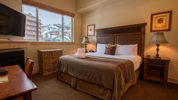 A hotel room with a bed, a desk, a television, a window with a view, and two bedside lamps.