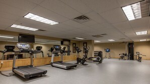 Un gimnasio con cintas de correr, elípticas y pelotas de ejercicios.