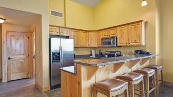 A kitchen with wooden cabinets, a stainless steel refrigerator, a microwave, and a granite countertop.