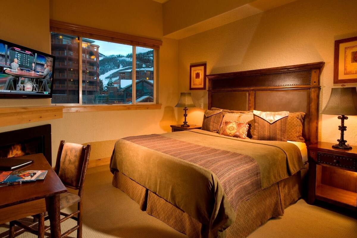 Una habitación de hotel con una cama, un escritorio, una silla, un televisor y una chimenea.