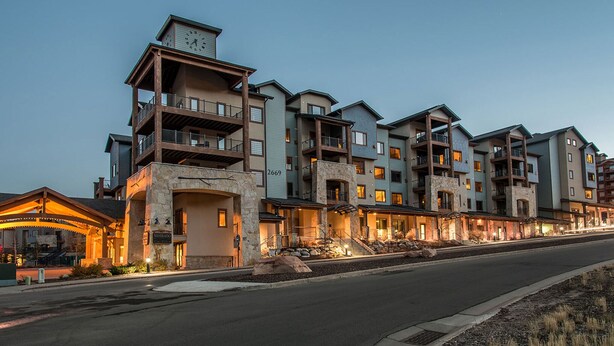 Un hotel de varios pisos con balcones, fachada de piedra y una entrada bien iluminada.