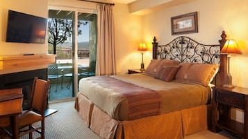 A hotel room with a bed, a TV, a desk with a chair, and a balcony with a view.