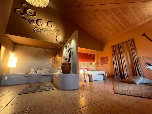 A modern interior with a seating area, a decorative wall with clocks, and a large plant centerpiece.