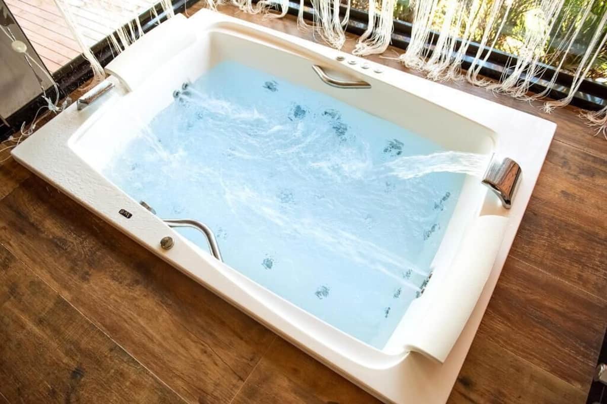 A rectangular hot tub with a white interior and a wooden floor surrounding it.