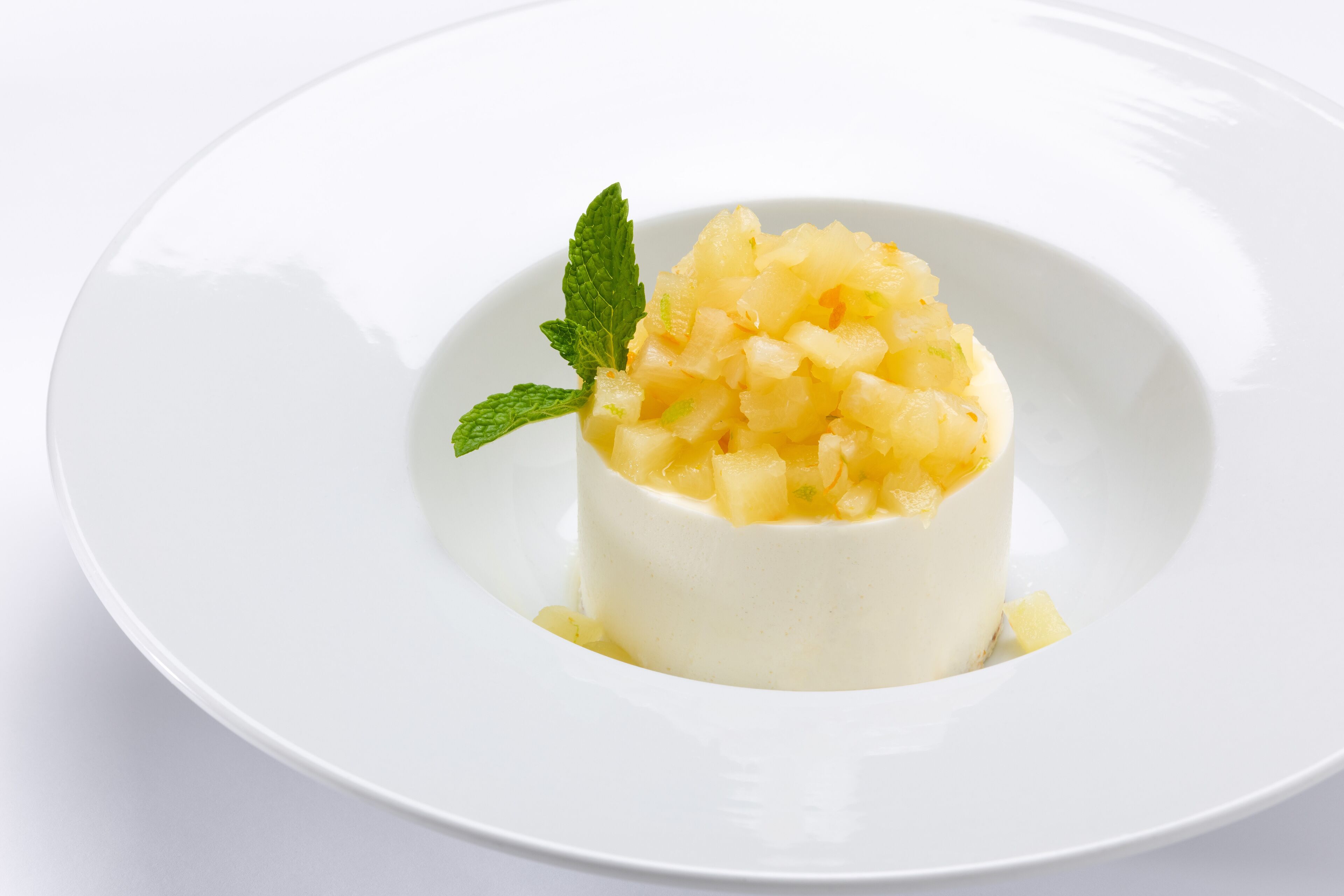 Un dessert servi dans une assiette blanche, décoré d’une feuille de menthe.