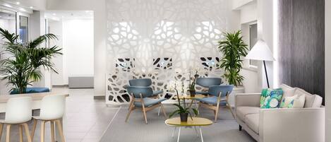 A modern living room with a sofa, two armchairs, a coffee table, and a decorative partition.