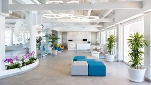 A modern hotel lobby with a reception desk, seating areas, and potted plants. - Hotel Tropical Park (Adeje)