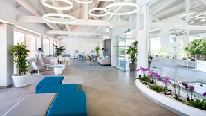 A spacious lobby with modern seating, a central water feature, and a high ceiling with circular light fixtures. - Hotel Tropical Park (Adeje)