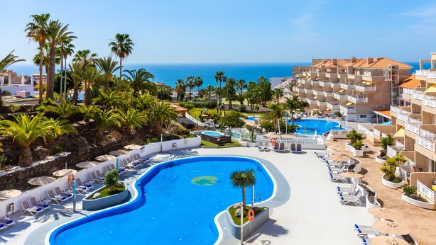A resort with a large pool, palm trees, and a view of the ocean. - Hotel Tropical Park (Adeje)
