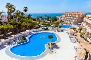 A resort with a large pool, palm trees, and a view of the ocean. - Hotel Tropical Park (Adeje)