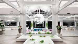 A modern lobby with a central seating area, a glass wall, and potted plants. - Hotel Tropical Park (Adeje)