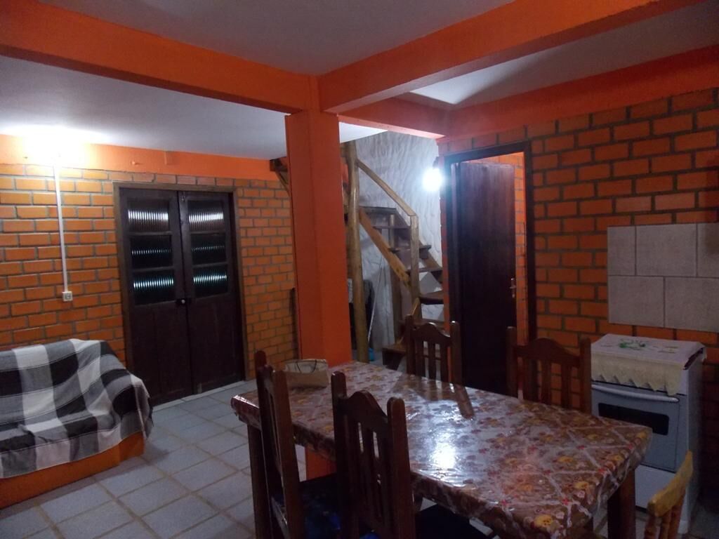 A dining area with a table and chairs, a brick wall, a staircase, and a refrigerator.