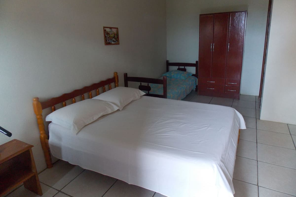 Una cama individual con cabecera de madera en una habitación con piso de baldosas.