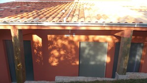 Un edificio con techo de tejas, dos puertas y un ventanal pequeño.
