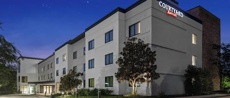 Un hotel Courtyard Marriott con diseño moderno, varios pisos y una entrada bien iluminada.