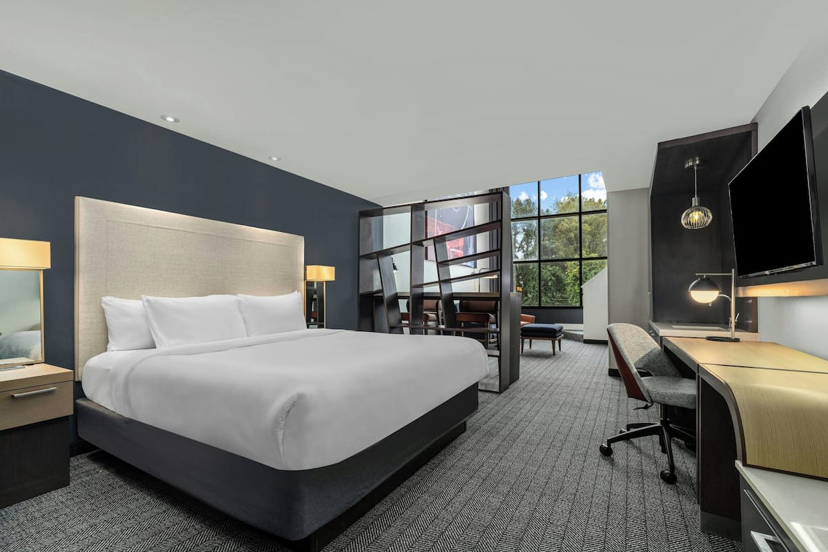 A modern hotel room with a large bed, a desk, and a TV.