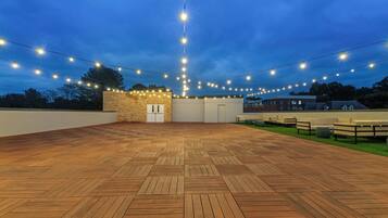 An outdoor patio area with a wooden floor, string lights, and outdoor seating.