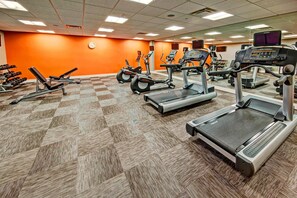A gym with various exercise equipment, including treadmills and weight machines, on a checkered floor. - Courtyard by Marriott Oxford (Oxford)
