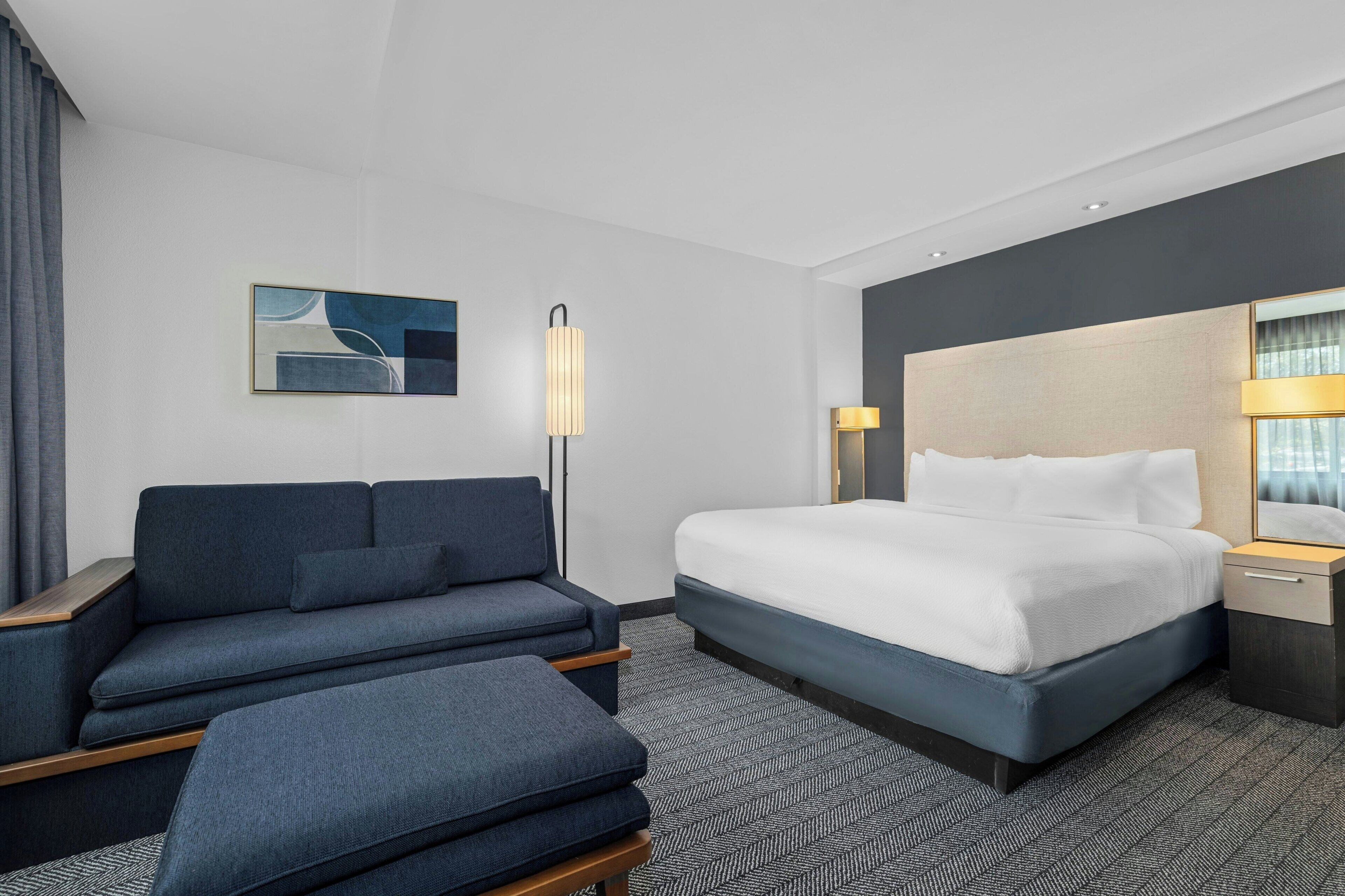 A modern hotel room with a large bed, a sofa, and a desk.