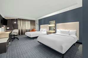 A hotel room with two beds, a desk, a chair, a TV, and a large window with curtains. - Courtyard by Marriott Oxford (Oxford)